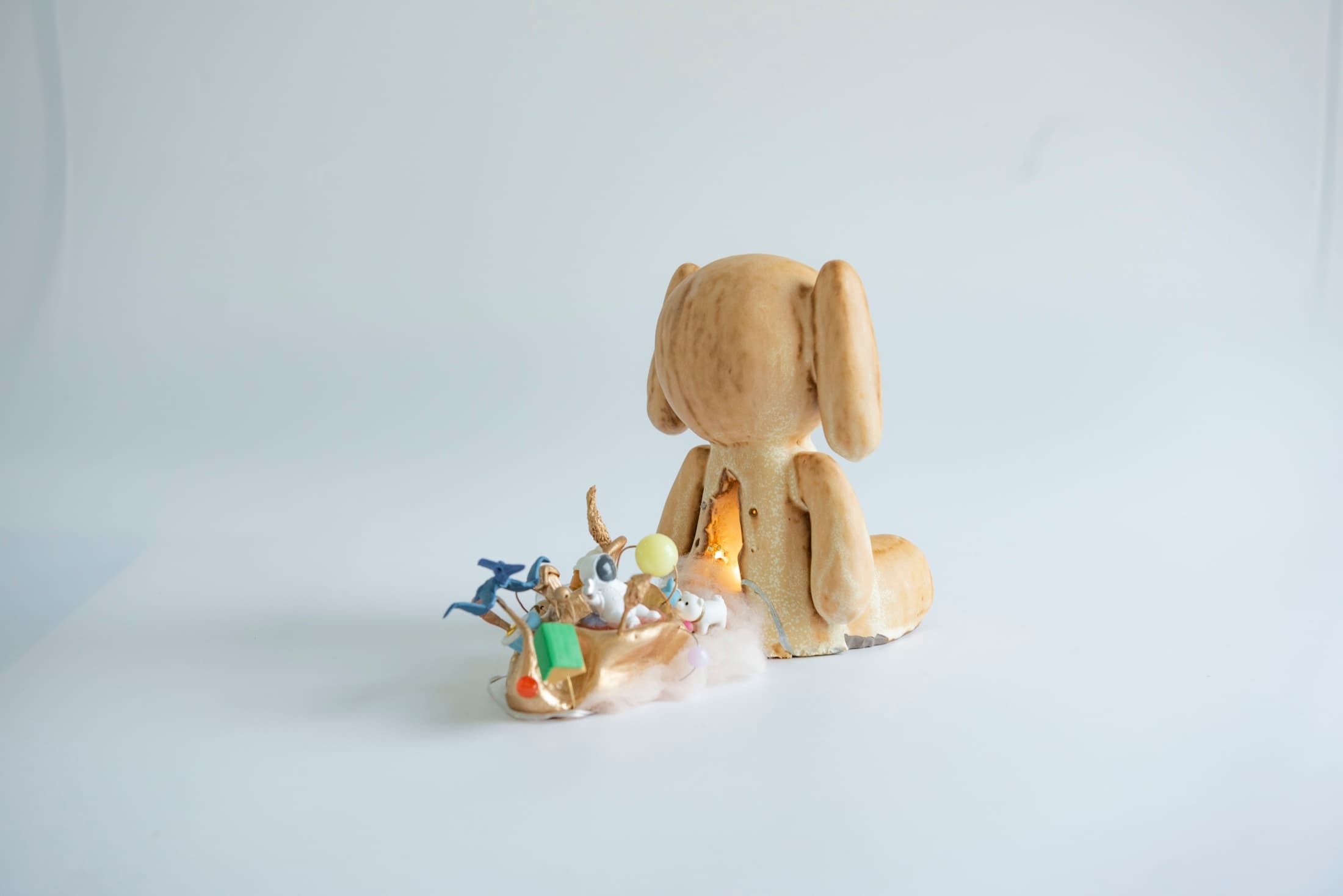 Hand-built ceramic rabbit facing a collection of small objects